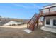 Backyard view with stairs and a deck that provide outdoor access to the second story, with grass and a few trees at 5810 Collier Bridge Ln, Hoschton, GA 30548