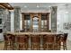Entertainment-ready bar with custom wood cabinets, stone pillars, and leather bar stools at 879 Big Horn Hollow, Suwanee, GA 30024