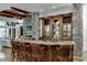 Basement bar with stone pillars, wooden cabinetry, and leather barstools at 879 Big Horn Hollow, Suwanee, GA 30024