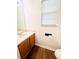 Half bath featuring wood floors, cabinet vanity, large mirror, and a window for natural light at 2717 Kristen Ct, Conyers, GA 30012