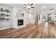 Living room area with hardwood floors, decorative fireplace, floating shelves, and large windows at 802 Oak Promenade Ln, Canton, GA 30115