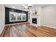 Cozy living room area with fireplace, hardwood floors, large windows, and dark accent wall at 802 Oak Promenade Ln, Canton, GA 30115