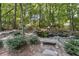 A peaceful backyard with a stone pond, bench, and natural landscaping surrounded by trees at 1400 Lamont Cir, Dacula, GA 30019