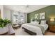 Bright bedroom featuring a green accent wall, a ceiling fan, and windows with patterned curtains at 584 Silver Moon Dr, Loganville, GA 30052
