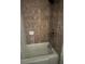 A bright bathroom showcasing the tub and shower tiled in neutral browns at 3230 Vanderbilt Nw Ln, Atlanta, GA 30318