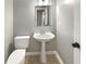 Compact powder room with pedestal sink, modern mirror, and neutral walls offers a convenient space for guests at 1615 Cheshire Ct, Lawrenceville, GA 30043