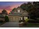 Charming home featuring a two-car garage, well-manicured landscaping, and a welcoming front porch at twilight at 8010 Majors Mill Dr, Cumming, GA 30041