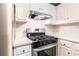 Close up of a stainless steel stove in a kitchen with white cabinets and gray countertops at 3950 Yancey Rd, Douglasville, GA 30135