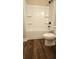 Bathroom with a modern white tub shower and a matching toilet, complemented by hardwood floors and black hardware at 724 Vinson Mountain Crossing Rd, Rockmart, GA 30153