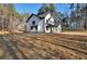 Side view of a modern farmhouse with white siding, black trim, and spacious yard ready for landscaping at 3785 Pilgrim Mill Rd, Cumming, GA 30041