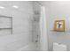Well-lit bathroom showcasing white tiles, shower with curtain, and glass shelf with framed artwork at 2479 Peachtree Ne Rd # 105, Atlanta, GA 30305