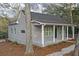 Side view of a gray cottage-style home with a welcoming front porch, gray roof, and manicured landscaping at 1815 River Ne St, Conyers, GA 30012