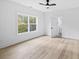 Spacious bedroom featuring light hardwood floors, a ceiling fan, and access to a well-lit bathroom at 1387 Mineral Springs Rd, Hoschton, GA 30548