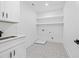 Clean laundry room featuring white cabinets, stylish patterned floors, and open shelving at 1387 Mineral Springs Rd, Hoschton, GA 30548