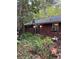 View of the backyard with a brick house featuring an overgrown garden and external air conditioning unit at 5655 Campbellton Sw Rd, Atlanta, GA 30331