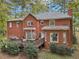 A view of the brick home's backyard and wooden deck surrounded by lush greenery and mature trees at 3047 Players Dr, Jonesboro, GA 30236