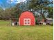 A red barn with white trim sits in the middle of the large green lawn at 1871 Weems E Rd, Locust Grove, GA 30248