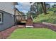 Backyard with a small deck, green grass and retaining wall with mulch at 6914 Fairway Trl, Austell, GA 30168