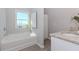 Bright bathroom featuring a bathtub, a window, light gray walls, and granite countertops at 6478 Beaver Creek Trl, Atlanta, GA 30349
