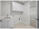 Well-equipped laundry room with white cabinets, a sink, and built-in shelving at 2735 Marie Way, Cumming, GA 30028