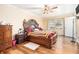 Spacious bedroom featuring hardwood floors, a ceiling fan, and a large ornate wooden bed frame at 112 Christopher Ln, Stockbridge, GA 30281