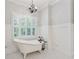 Elegant bathroom featuring a clawfoot tub, chandelier, wainscoting and large window with plantation shutters at 220 Spring Branch Dr, Canton, GA 30115