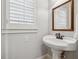 Bright powder room featuring a pedestal sink, mirror, and plantation shutters at 220 Spring Branch Dr, Canton, GA 30115