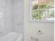 Bright bathroom featuring white marble tile and natural lighting through a window at 1830 Mayfield Rd, Alpharetta, GA 30009