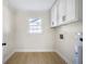 Well-lit laundry room with storage cabinets, light colored walls, and light colored wood floors at 1830 Mayfield Rd, Alpharetta, GA 30009