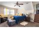 Cozy bedroom with a ceiling fan, comfortable seating, a plush rug, and a bed dressed in blue and yellow accents at 1236 Country Pine Dr, Ellenwood, GA 30294