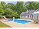 View of the back of a house with an inground pool, slide, basketball hoop, patio table and umbrella at 160 Cross Rd, Covington, GA 30016