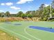 Outdoor basketball court with vibrant green and blue surfaces, surrounded by trees and a playground in the background at 424 Lake Point Trce, Canton, GA 30114