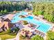 Aerial view showcases a vast community pool area surrounded by trees, featuring multiple pools, slides, and lounging spaces at 424 Lake Point Trce, Canton, GA 30114
