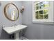 Bathroom featuring pedestal sink, decorative mirror, sconce lighting and large window at 7300 Chattahoochee Bluff Dr, Atlanta, GA 30350