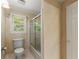 Neutral toned bathroom featuring a toilet, shower with glass doors, and a bright window overlooking the outdoors at 7300 Chattahoochee Bluff Dr, Atlanta, GA 30350
