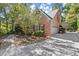 Side view of a brick home highlighting the driveway leading to a two-car garage and lush landscaping at 7300 Chattahoochee Bluff Dr, Atlanta, GA 30350