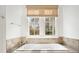 Close-up of bathtub with stone surround and window with woven shade at 420 Argonne Nw Dr, Atlanta, GA 30305