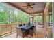 Covered back porch with wood flooring, ceiling fan, a table with six chairs and views of the wooded backyard at 3780 Tamiami Trl, Cumming, GA 30041