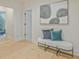 Hallway featuring an art piece, light wood floors, neutral paint, and a bench with pillows at 3780 Tamiami Trl, Cumming, GA 30041