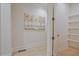 Hallway with light wood floors, a painting, an open door, and wall shelves at 3780 Tamiami Trl, Cumming, GA 30041