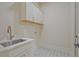 Bright laundry room featuring a sink, white cabinets, and tile floors at 3780 Tamiami Trl, Cumming, GA 30041