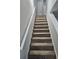Carpeted staircase leading to the upper level, featuring white handrails and neutral walls at 6500 Wellington Chase Ct, Lithonia, GA 30058