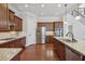 Kitchen with wood floors, wooden cabinets, and a large granite countertop island with pendant lighting at 2420 Bronze Ct, Cumming, GA 30041