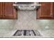 Close up of the kitchen with granite countertops, tiled backsplash and stainless gas cooktop at 2420 Bronze Ct, Cumming, GA 30041