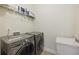Well-equipped laundry room with modern washer and dryer, complemented by a utility sink and storage shelves at 2420 Bronze Ct, Cumming, GA 30041
