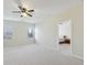 Bright living room features plush carpeting, a ceiling fan, and multiple windows for natural light at 2420 Bronze Ct, Cumming, GA 30041