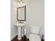 Cozy powder room featuring a pedestal sink, decorative mirror, and a modern toilet with dark wood floors at 2420 Bronze Ct, Cumming, GA 30041