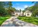 Elegant two-story white home featuring a circular driveway, manicured lawn and mature trees against a blue sky at 3488 Tuxedo Nw Rd, Atlanta, GA 30305