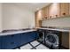 Modern laundry room with blue cabinets, granite countertops, wood cabinets, and front-loading machines at 3488 Tuxedo Nw Rd, Atlanta, GA 30305