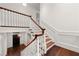 Elegant staircase featuring wood steps, white railings, and a view of the front door at 3488 Tuxedo Nw Rd, Atlanta, GA 30305